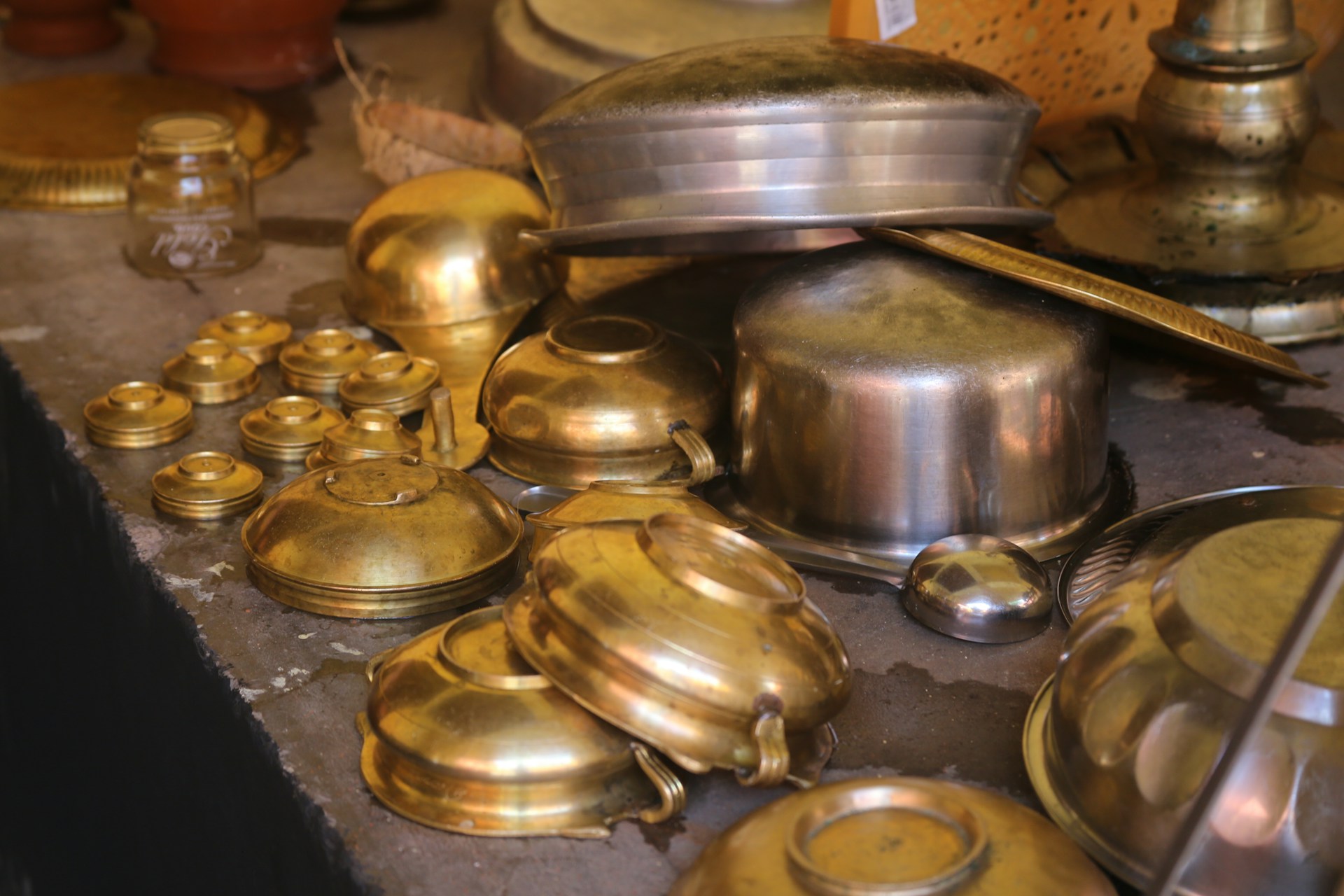 a table topped with lots of brass pots and pans