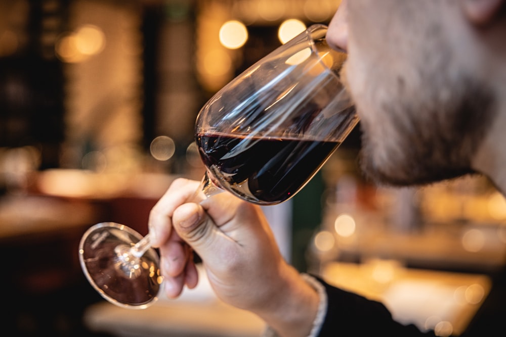 a man drinking a glass of red wine