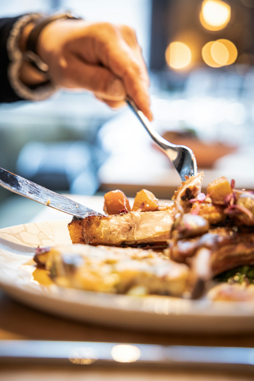 a person is cutting a piece of food on a plate