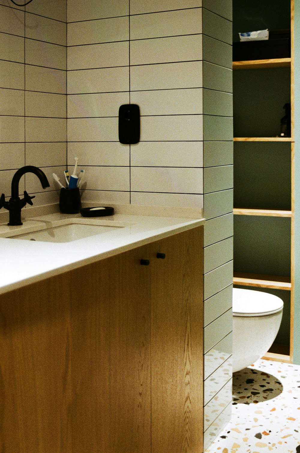 a bathroom with a sink, toilet and shelves