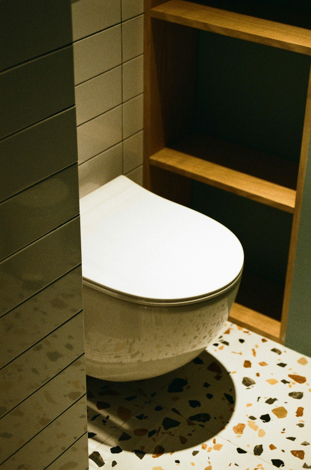 a white toilet sitting in a bathroom next to a book shelf