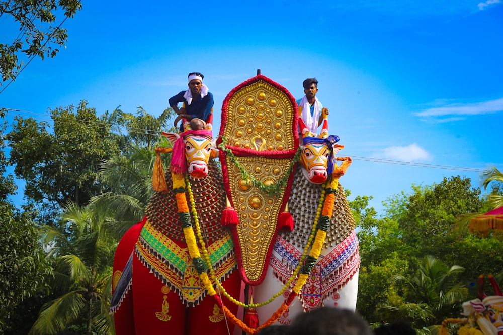 two men riding on the back of a decorated elephant