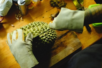a person cutting a durian fruit on a cutting board