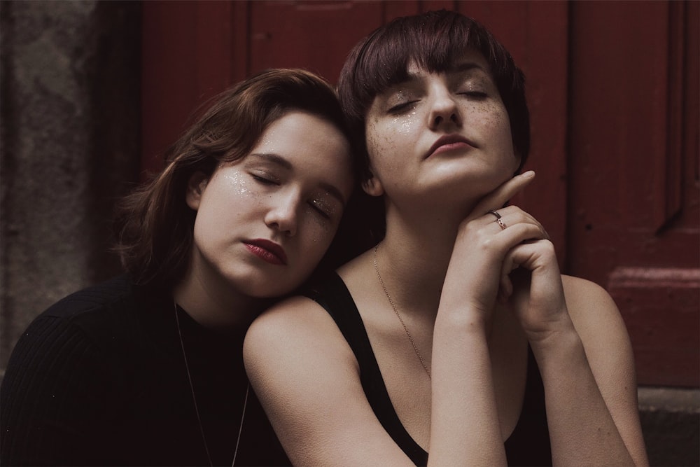 two women sitting next to each other with their eyes closed