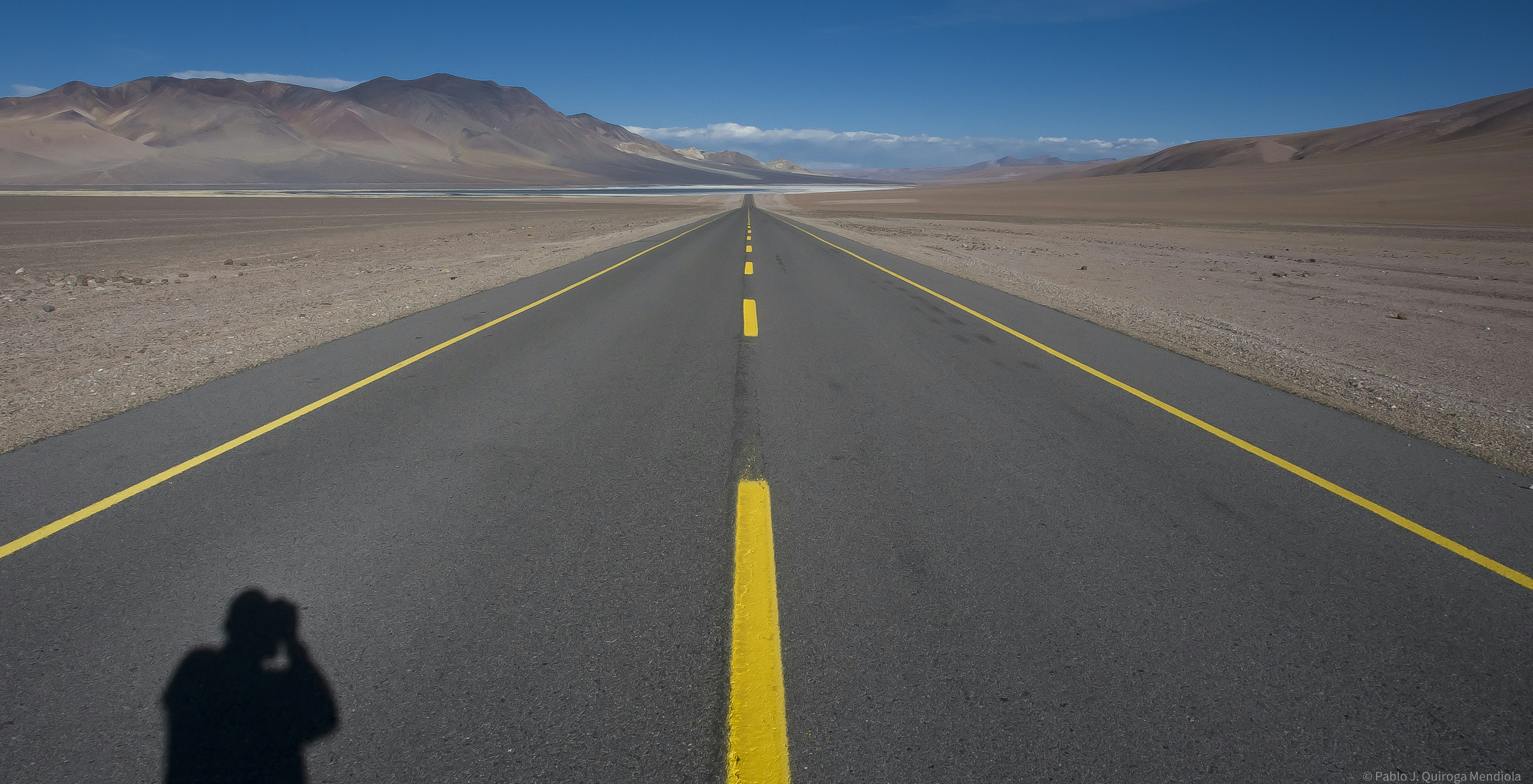 a person taking a picture of a road in the desert (Photo by Pablo Quiroga on Unsplash)