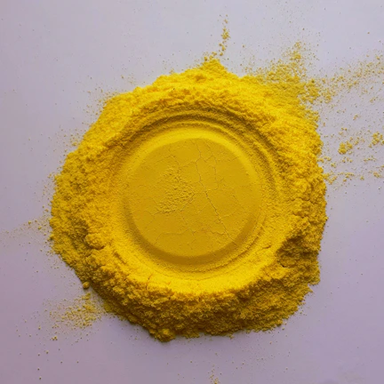 Close-up of bright yellow dye powder in a stainless steel container.