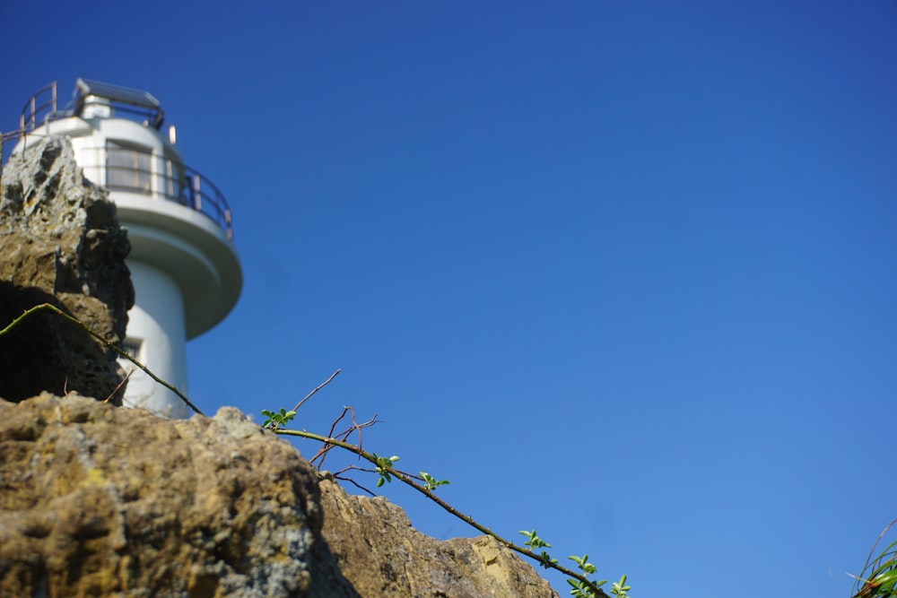 a white light house on top of a rocky cliff