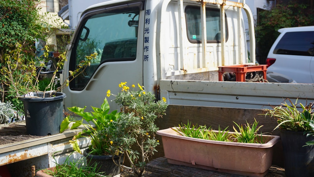 a white truck parked next to a pile of potted plants