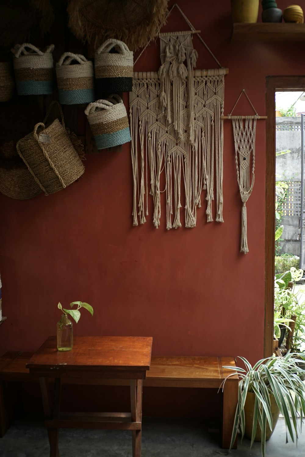 a room with a wooden table and hanging baskets on the wall
