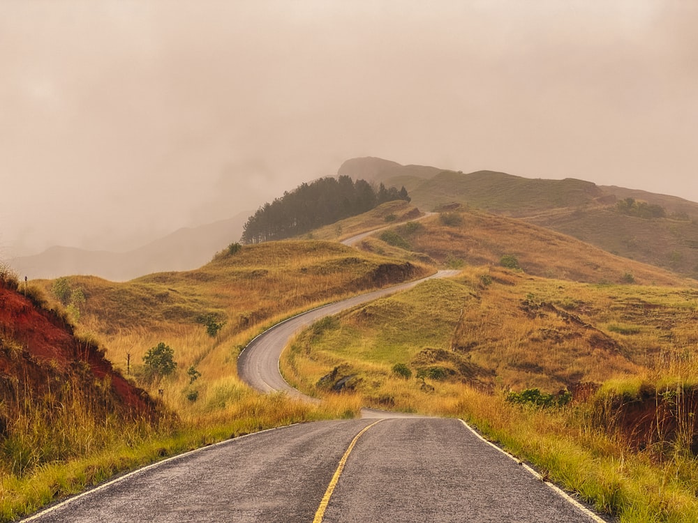 an empty road in the middle of a hilly area