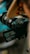 A digital camera is positioned for a shot, with its viewfinder displaying an image of a person silhouetted against a natural backdrop. The scene is focused on the camera and its screen, highlighting the camera's intricate features and the process of capturing a moment.