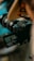 A digital camera is positioned for a shot, with its viewfinder displaying an image of a person silhouetted against a natural backdrop. The scene is focused on the camera and its screen, highlighting the camera's intricate features and the process of capturing a moment.