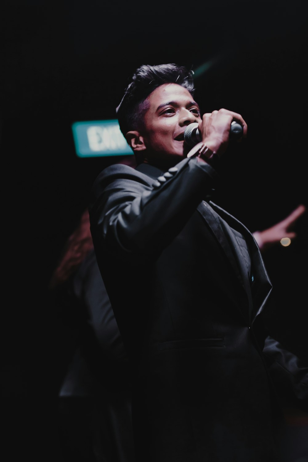 a man in a black suit singing into a microphone