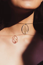 a woman wearing a necklace with a leaf on it