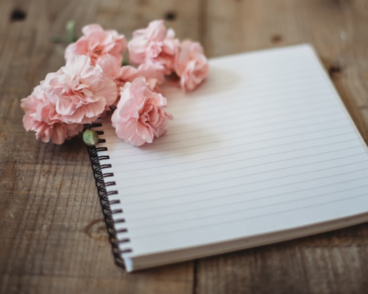 A close-up of a notebook page featuring a delicate floral border design in soft pastel colors.