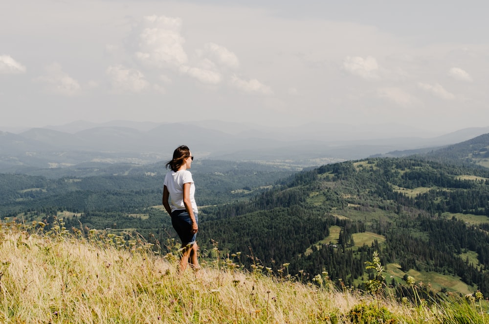 a woman standing on top of a lush green hillside