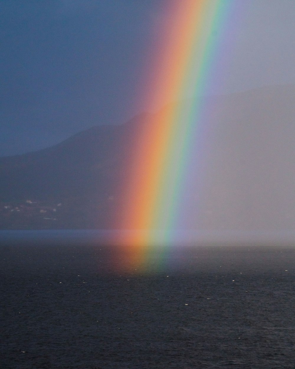 a rainbow shines in the sky over the ocean