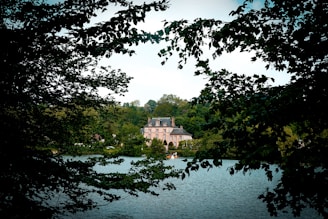 a large house sitting on top of a lake surrounded by trees