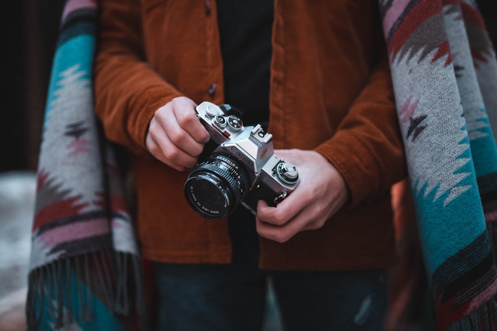 una persona che tiene in mano una macchina fotografica e una coperta