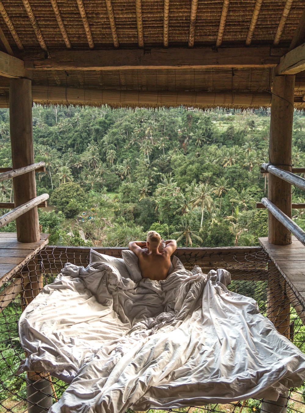 a man laying in a hammock on top of a lush green forest