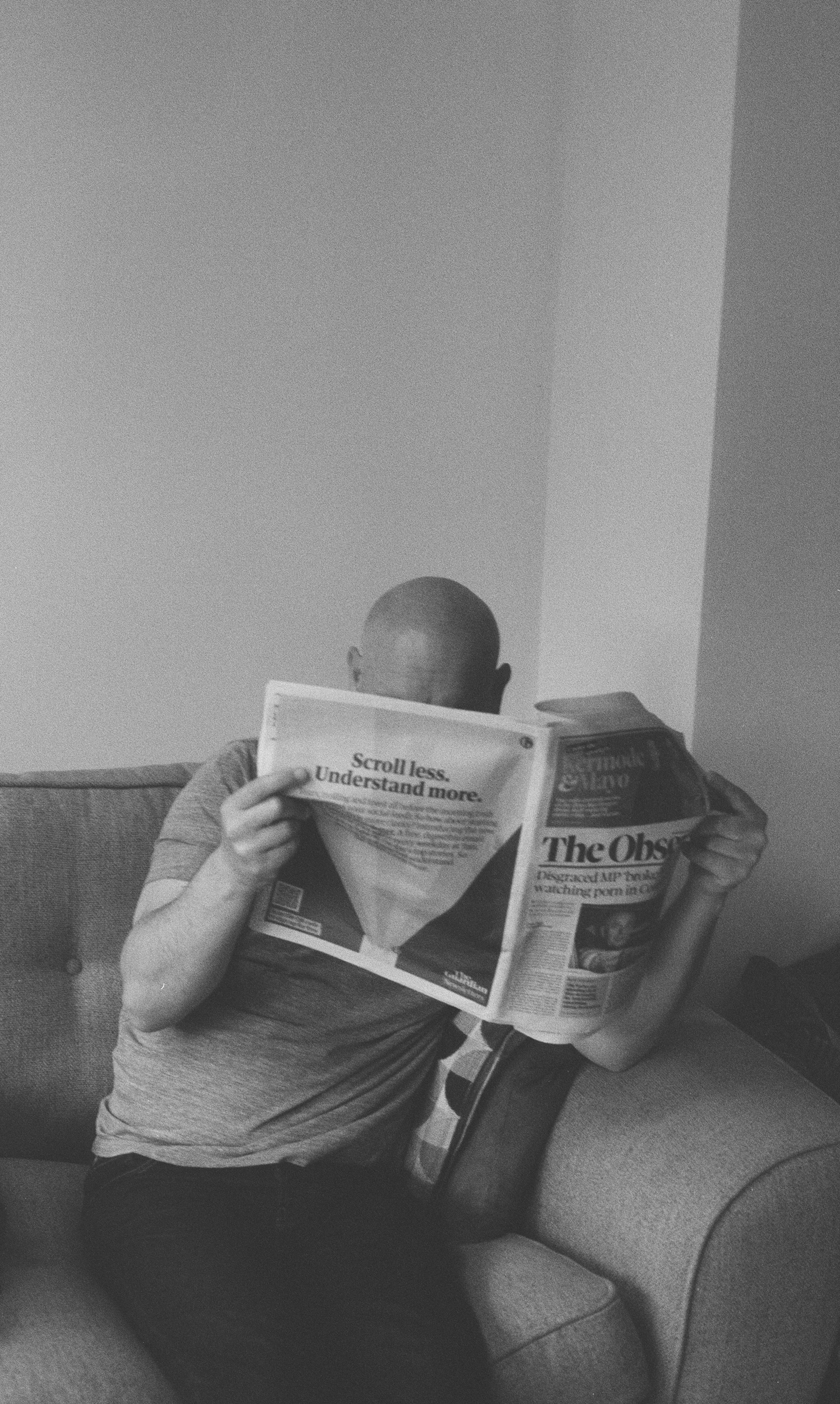 a man sitting on a couch reading a newspaper