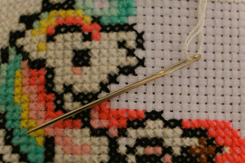 a close up of a needle and a cross stitch pattern