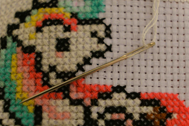 A needle resting on a cross-stitch piece in progress