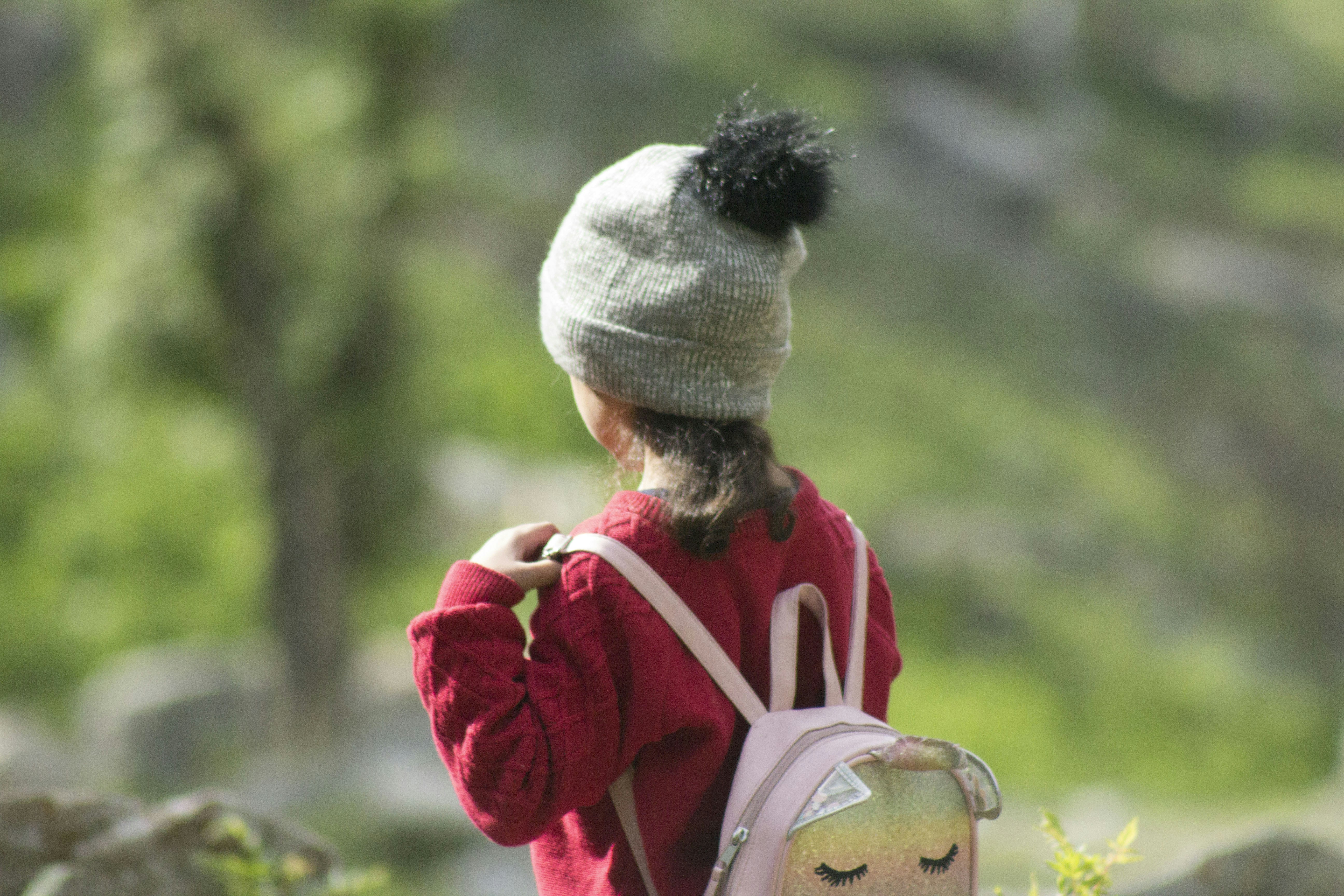Jeune enfant autonome avec un sac à dos, explorant la nature, illustrant le concept de voyager en Montessori.