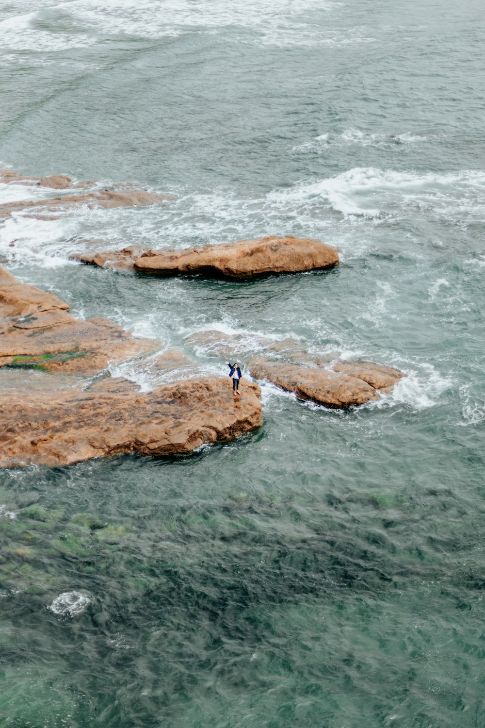 a person standing on a rock near the ocean