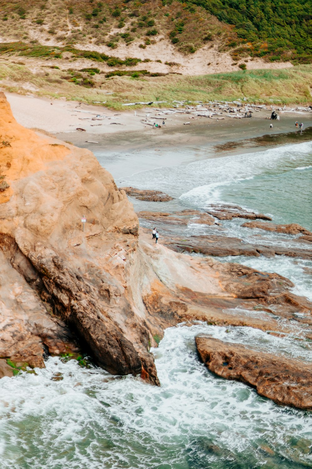 a group of people standing on top of a cliff next to the ocean