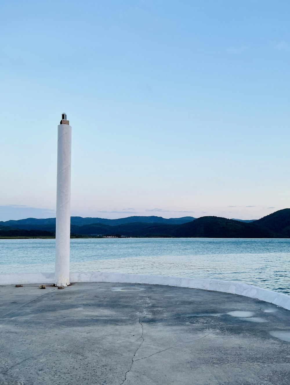 a tall white pillar sitting in the middle of a lake