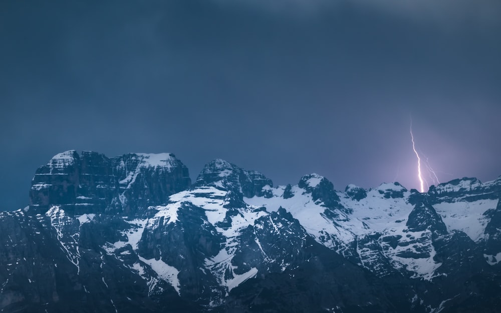 a lightning strikes in the sky over a mountain range