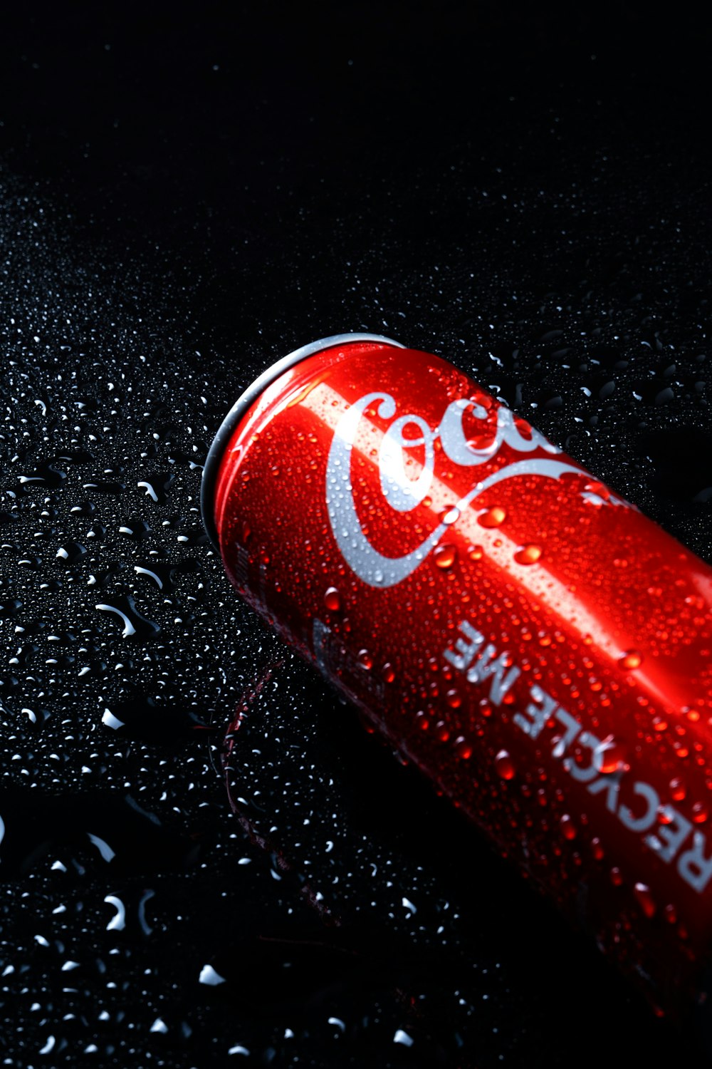 a can of coca cola sitting on top of a wet surface