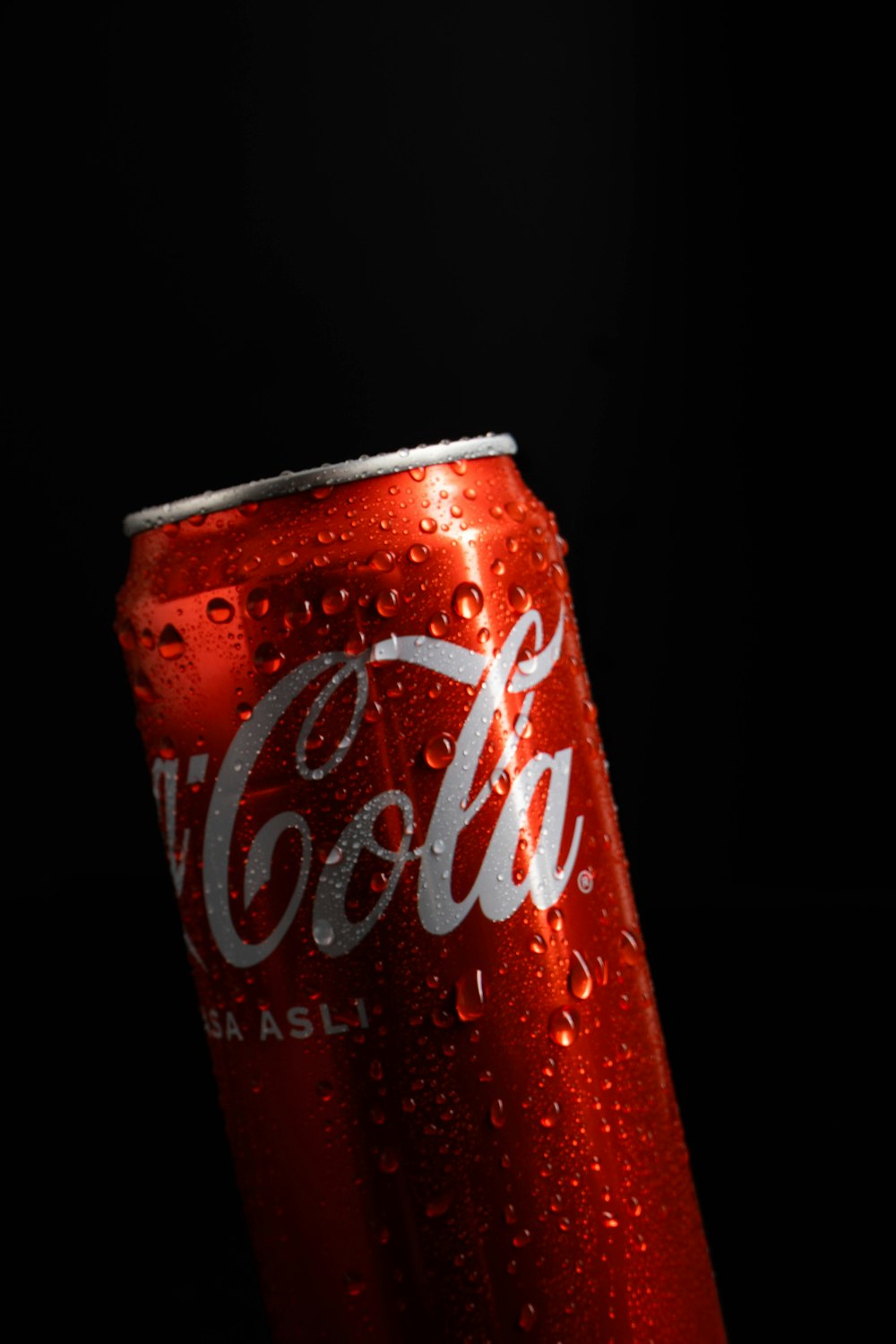 a can of coca - cola on a black background
