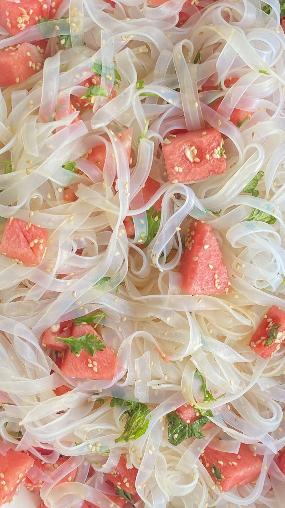 a close up of a plate of food with noodles and watermelon