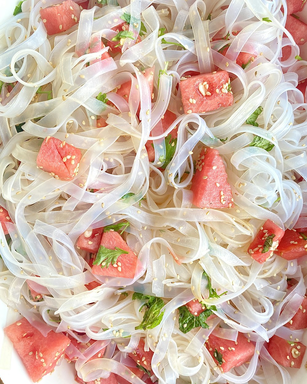 a close up of a plate of food with noodles and watermelon