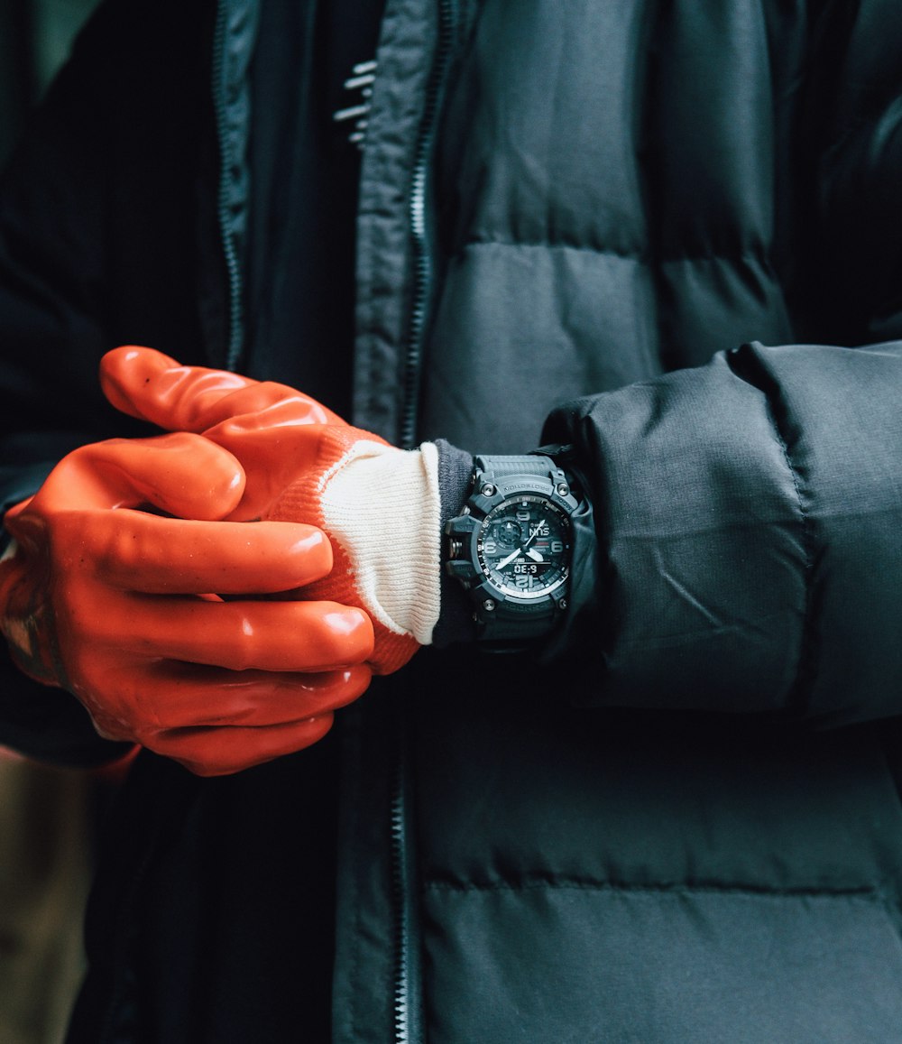 a person wearing orange gloves and a watch