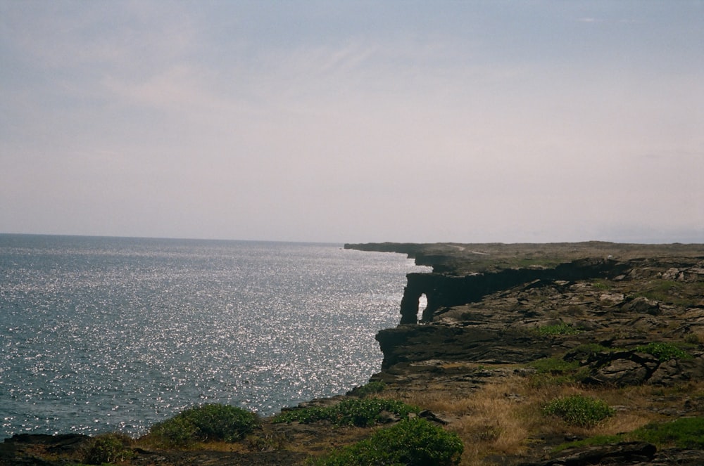 uma pessoa de pé à beira de um penhasco com vista para o oceano