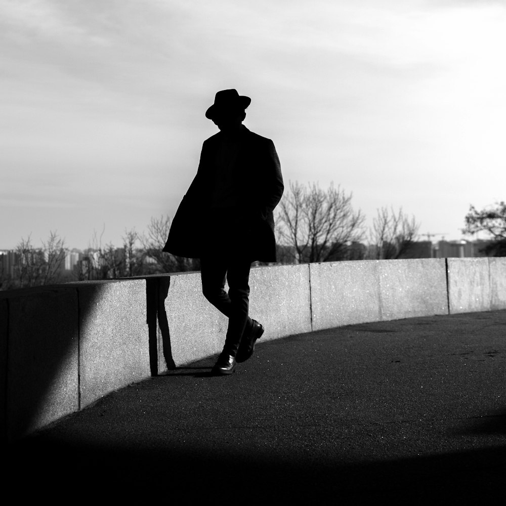 a black and white photo of a man in a coat and hat