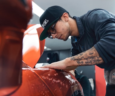 a man in a black shirt and hat waxing a car