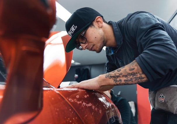 a man in a black shirt and hat waxing a car