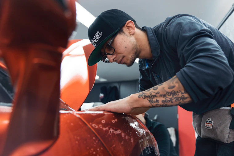 a man in a black shirt and hat waxing a car