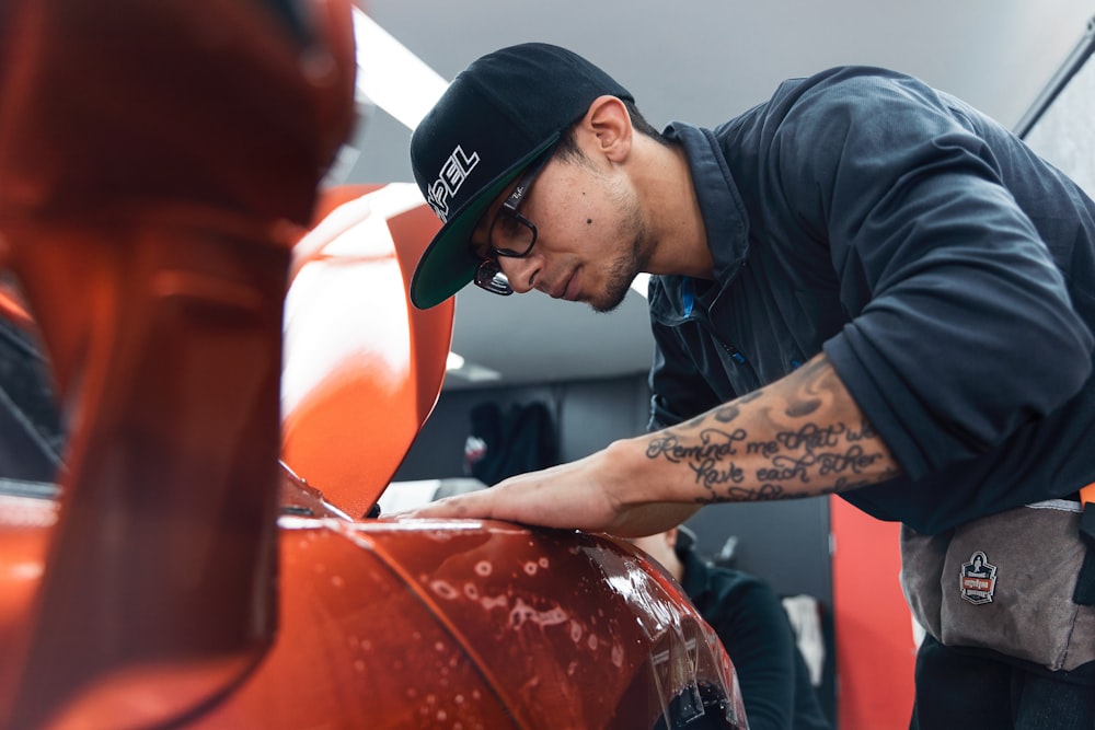 a man in a black shirt and hat waxing a car