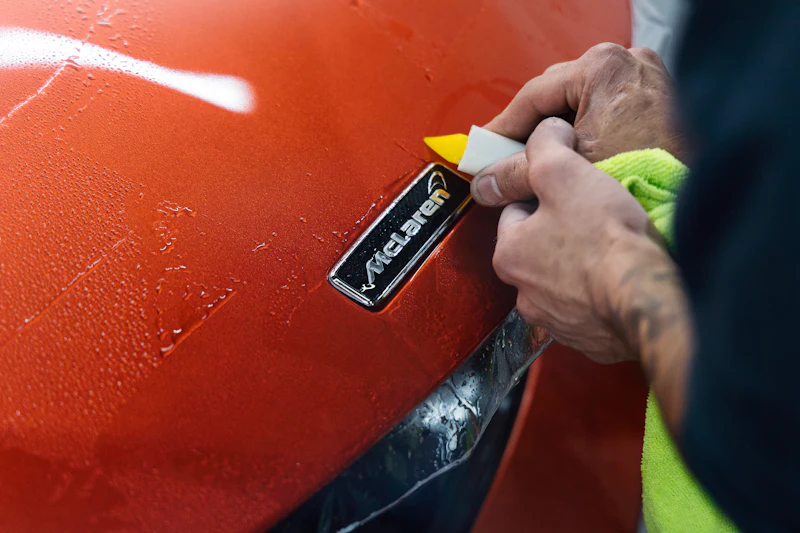 Installer applying clear film to the hood of a sports car