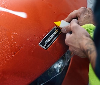 a man polishing the hood of a red car