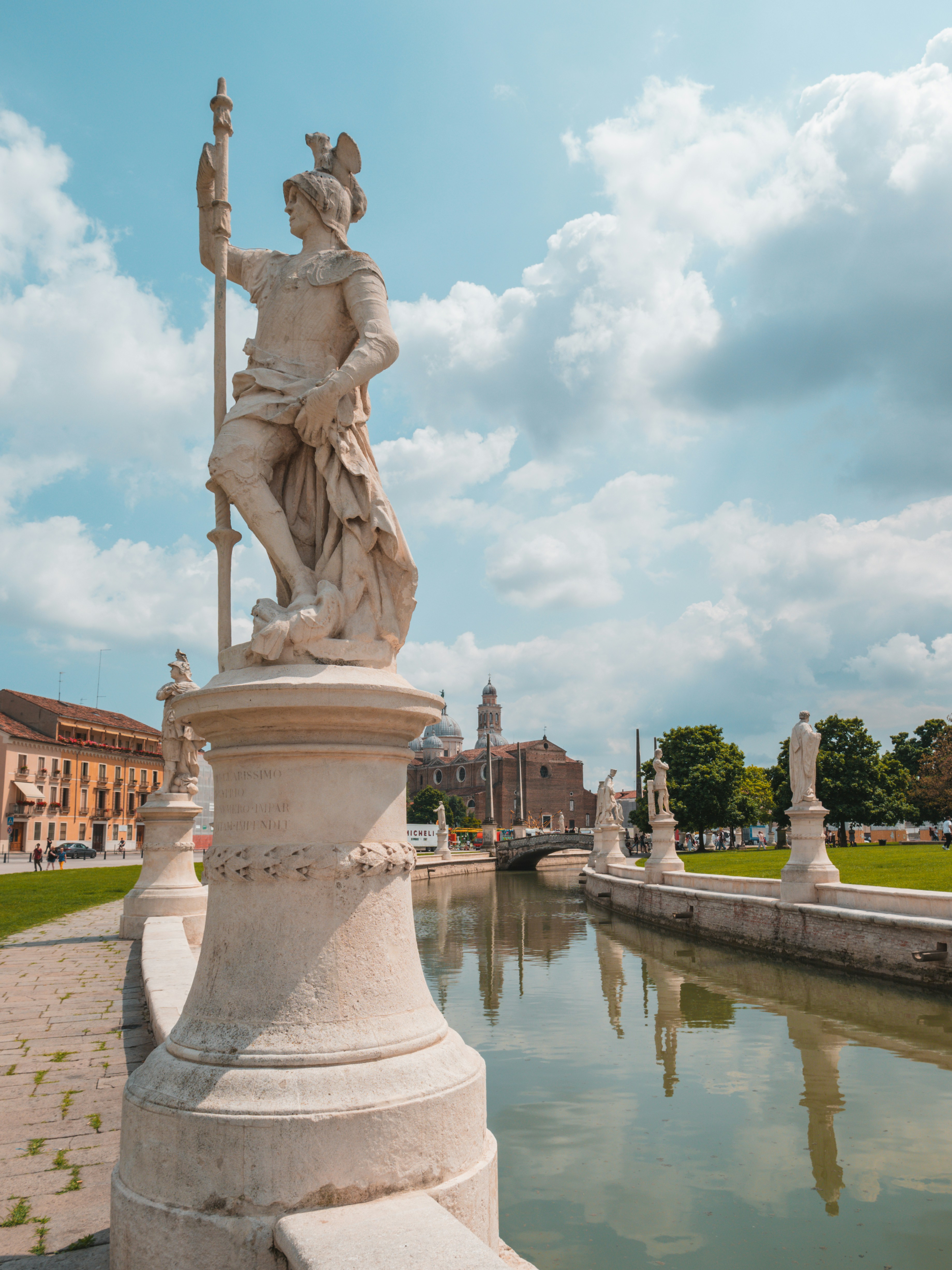 a statue of a woman holding a lamp next to a body of water