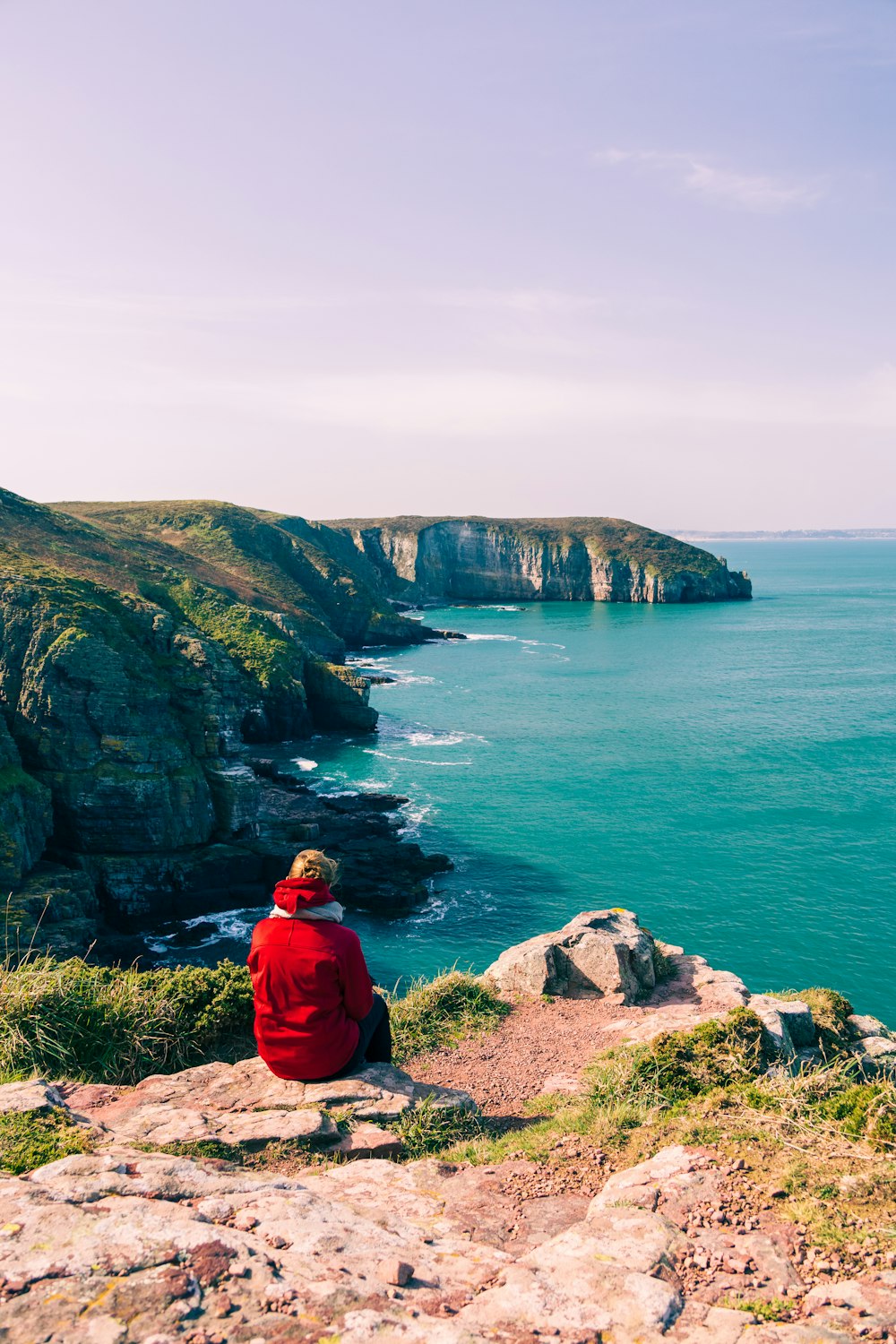 a person sitting on a cliff overlooking the ocean