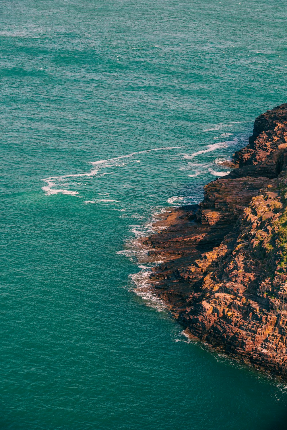 a boat is out on the water near a cliff