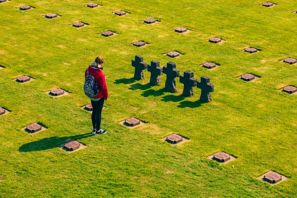 una persona in piedi in un campo con un mucchio di sculture