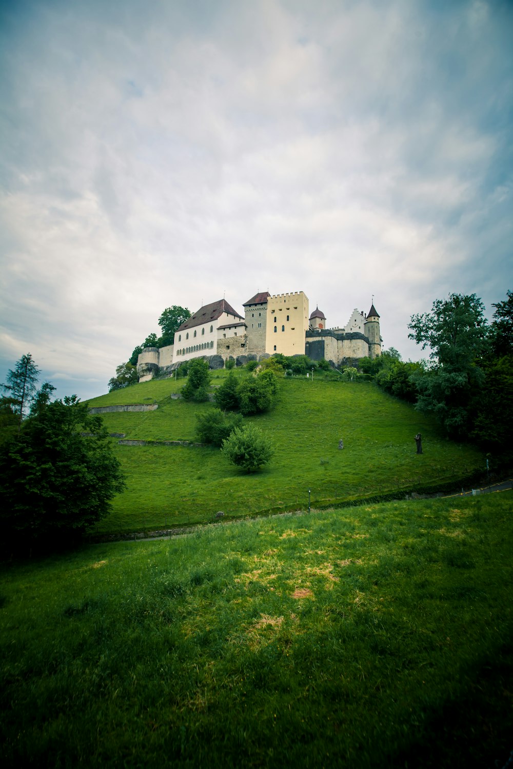 a large white building on top of a green hill